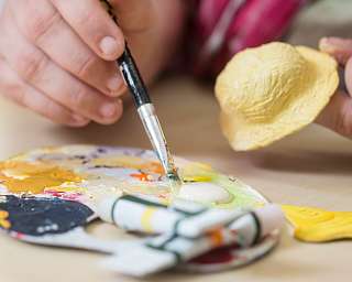 Ein Künstler malt mit einem Pinsel auf einer Farbpalette.