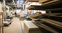 Innenansicht einer Werkstatt mit Holzplatten und Maschinen.