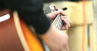 Nahaufnahme einer Hand, die eine Gitarre spielt.