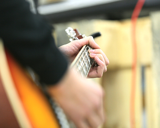Nahaufnahme von Händen, die eine Gitarre spielen.
