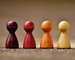 Vier Holzfiguren in verschiedenen Farben stehen nebeneinander.