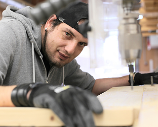 Ein Handwerker arbeitet an einem Holzstück in einer Werkstatt.