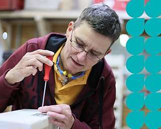 Eine Person benutzt einen Schraubendreher, um etwas zu reparieren.