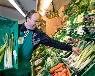Ein Mitarbeiter sortiert frisches Gemüse in einem Bio-Laden.