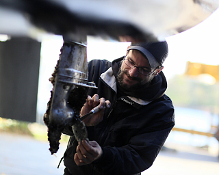 Ein Mann reinigt einen Bootsmotor in einer Werkstatt.