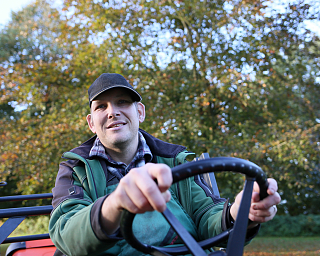 Lächelnder Mann fährt einen Traktor im Freien.