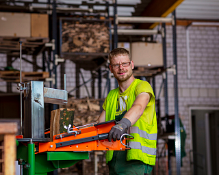 Ein Mann bedient eine Holzverarbeitungsmaschine in einer Werkstatt.
