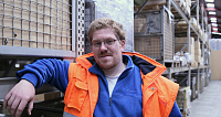 Ein Mann in orangefarbener Sicherheitsjacke steht im Lager.