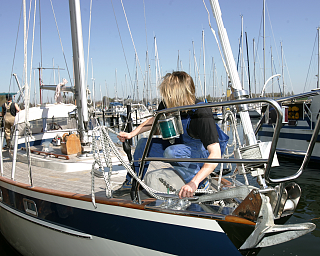 Eine Person arbeitet an einem Segelboot im Hafen.