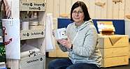 Eine Frau zeigt ein Produkt in einem Geschäft mit verschiedenen Artikeln.