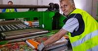 Arbeiter sortiert Blumenerde in einer Fabrik.