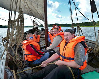 Sechs Personen in Rettungswesten auf einem Boot auf dem Wasser.