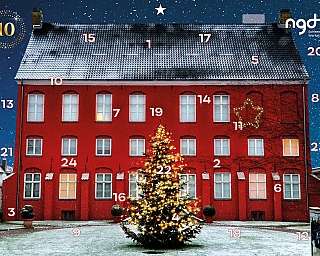 Rotes Gebäude mit Weihnachtsbaum und Schneefall im Hintergrund.