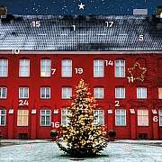 Rotes Gebäude mit Weihnachtsbaum und Schneefall im Hintergrund.