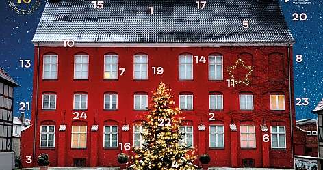 Rotes Gebäude mit Weihnachtsbaum und Schneefall im Hintergrund.