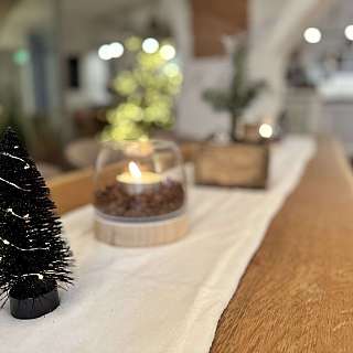 Dekoration mit einem schwarzen Weihnachtsbaum und Kerze auf einem Tisch.
