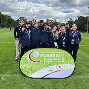 Gruppenfoto unserer Fussball-Mannschaft, die vor einem Schild steht. Auf dem Schild steht: Deutsche Meisterschaft Fussball, der Werkstätten für behinderte Menschen, DFB-Stiftung Sepp Herberger, Deutscher Behindertensportverband e.V. und BAG WfbM